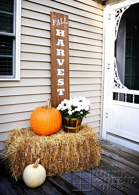 mums and pumpkin arrangement on straw bale on porch with sign